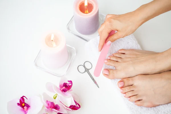 Closeup of beautiful woman legs getting pedicure at home