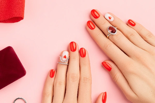 Womans hands with red manicure on pink background. Valentines day nail design